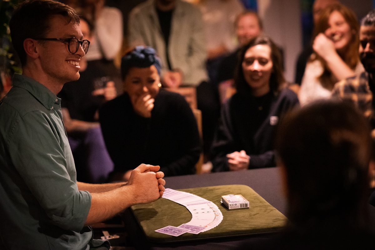 Sam King performing a close-up card magic show to a captivated audience