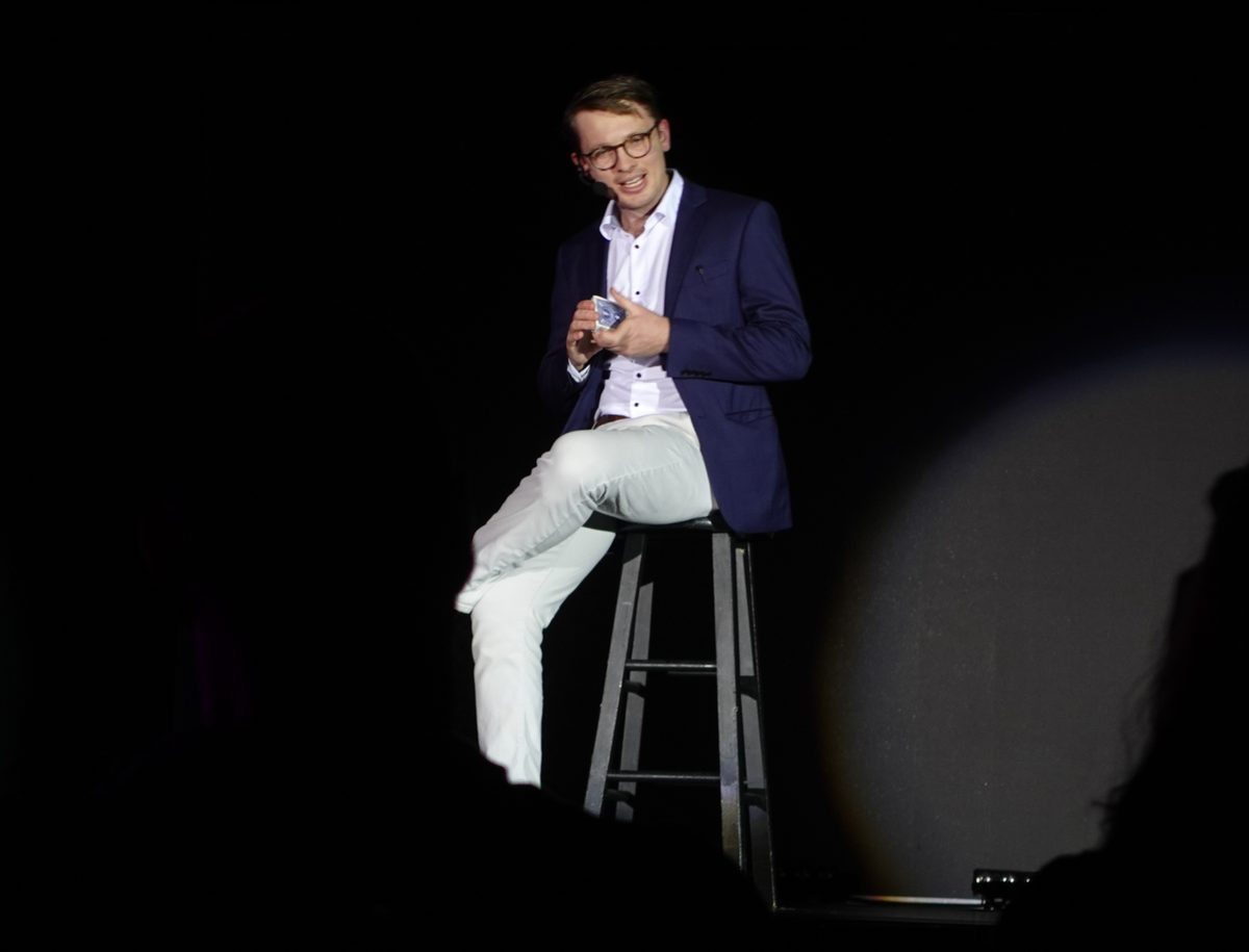 Sam King performing a spotlit stage magic show